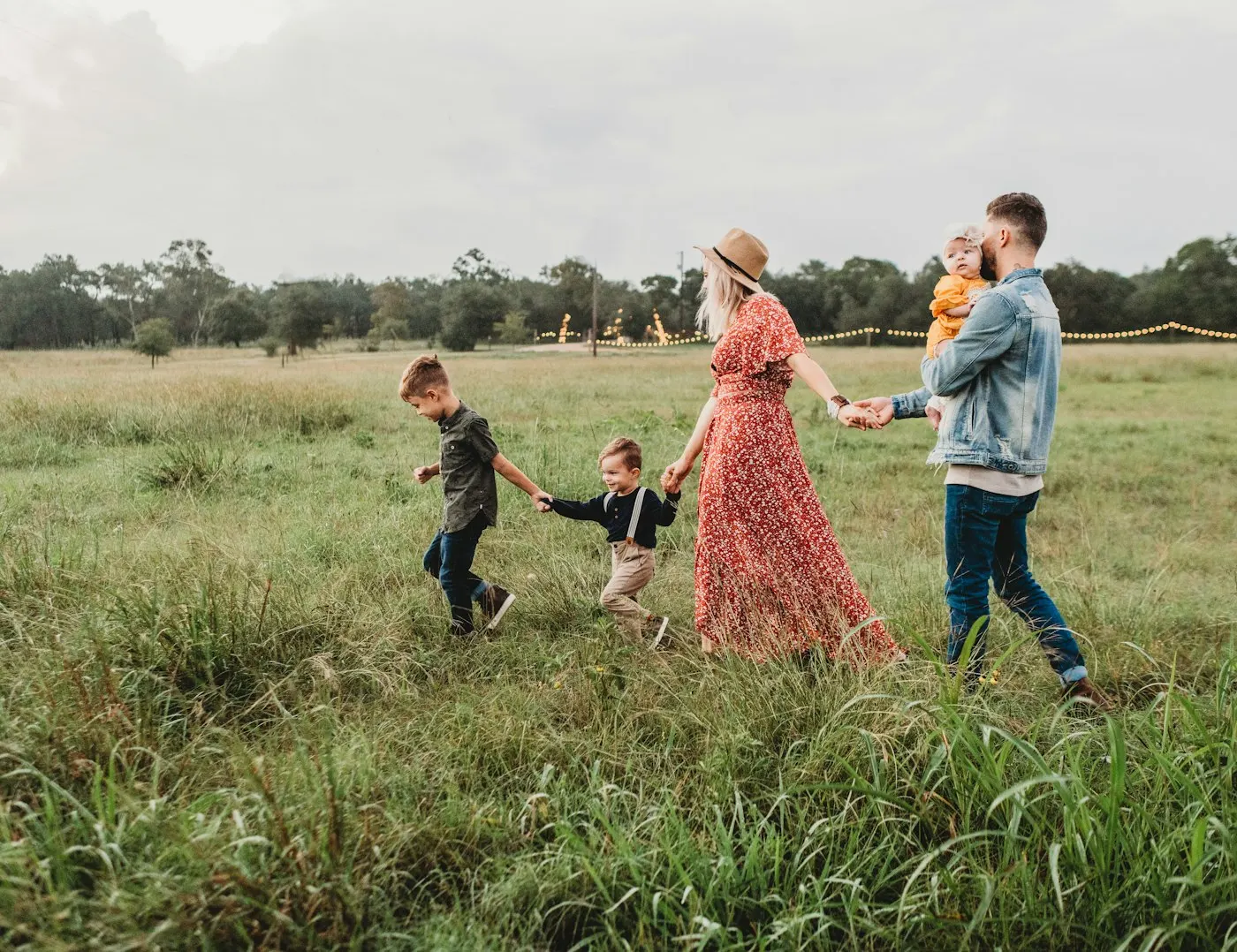 A family walking together through a sunlit golden field at the end of the day.